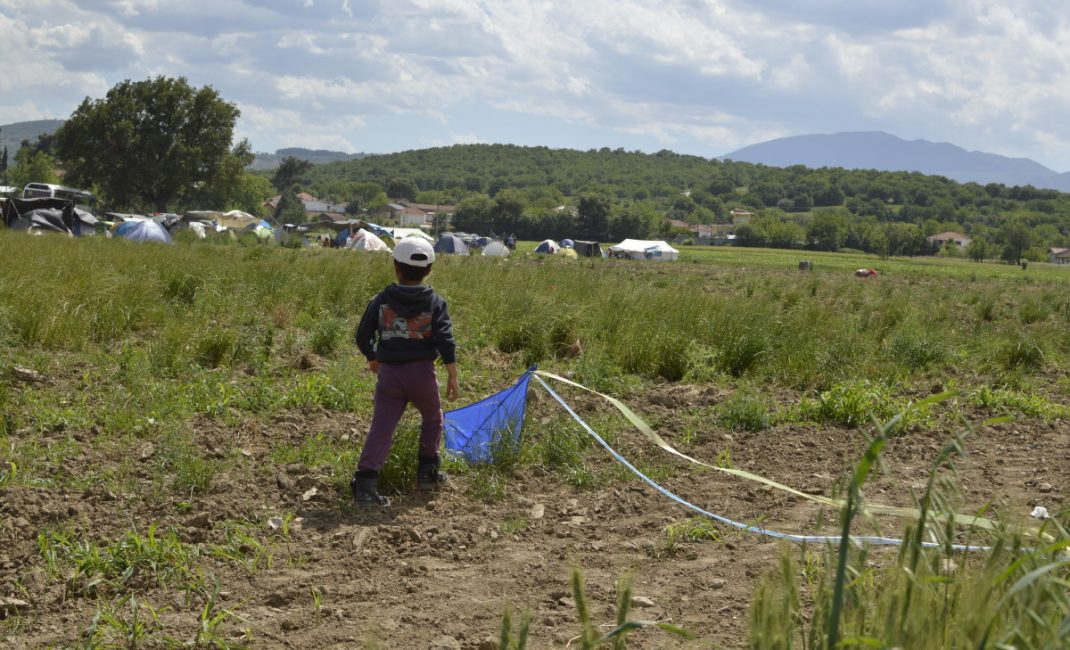 A kid plays with his kite away from the settlement of Idomeni