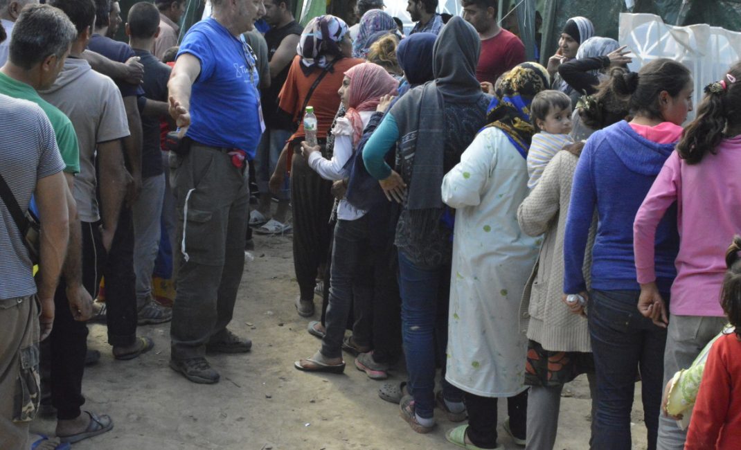 A volunteer divide men’s queue from the women and children’s one during a clothes distribution
