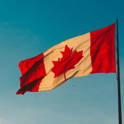 A large Canadian flag flying against a blue sky.