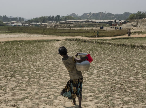 A Rohingya girl carries water to her camp