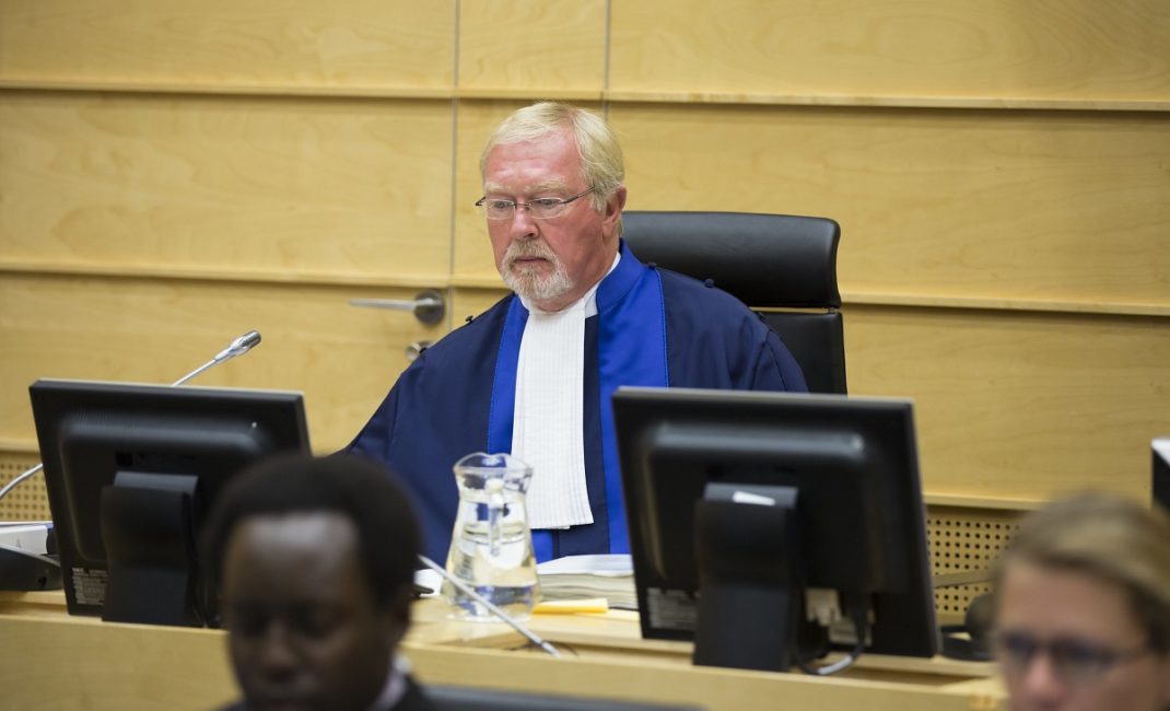 Judge Howard Morrison is wearing robes and seated at a desk at The Hague during a hearing for review concerning reduction of sentence of Mr Thomas Lubanga Dyilo in 2015