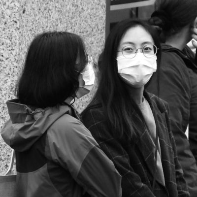 A black and white photograph of two young people wearing covid face masks