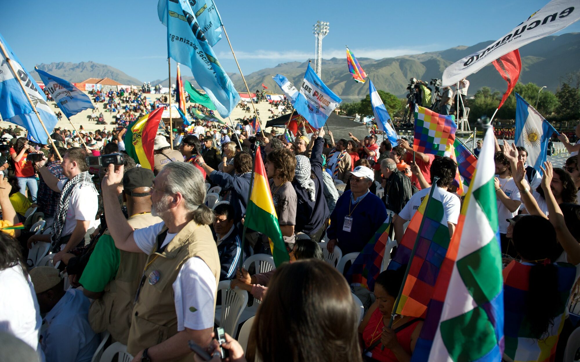 Cochabamba Bolivia World People's Conference on Climate Change and the Rights of Mother Earth. People are marching and holding various coloured flags.