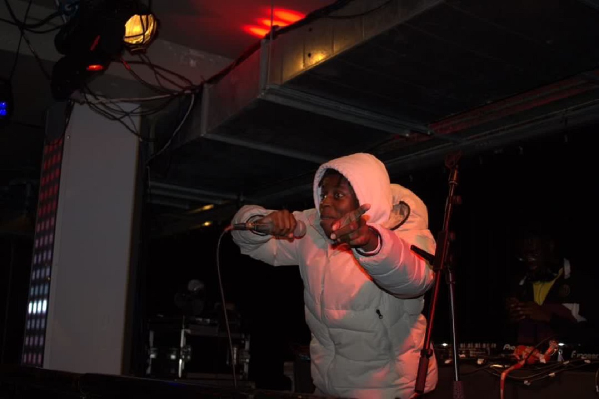 The author Xaymaca holding a microphone and performing on stage.