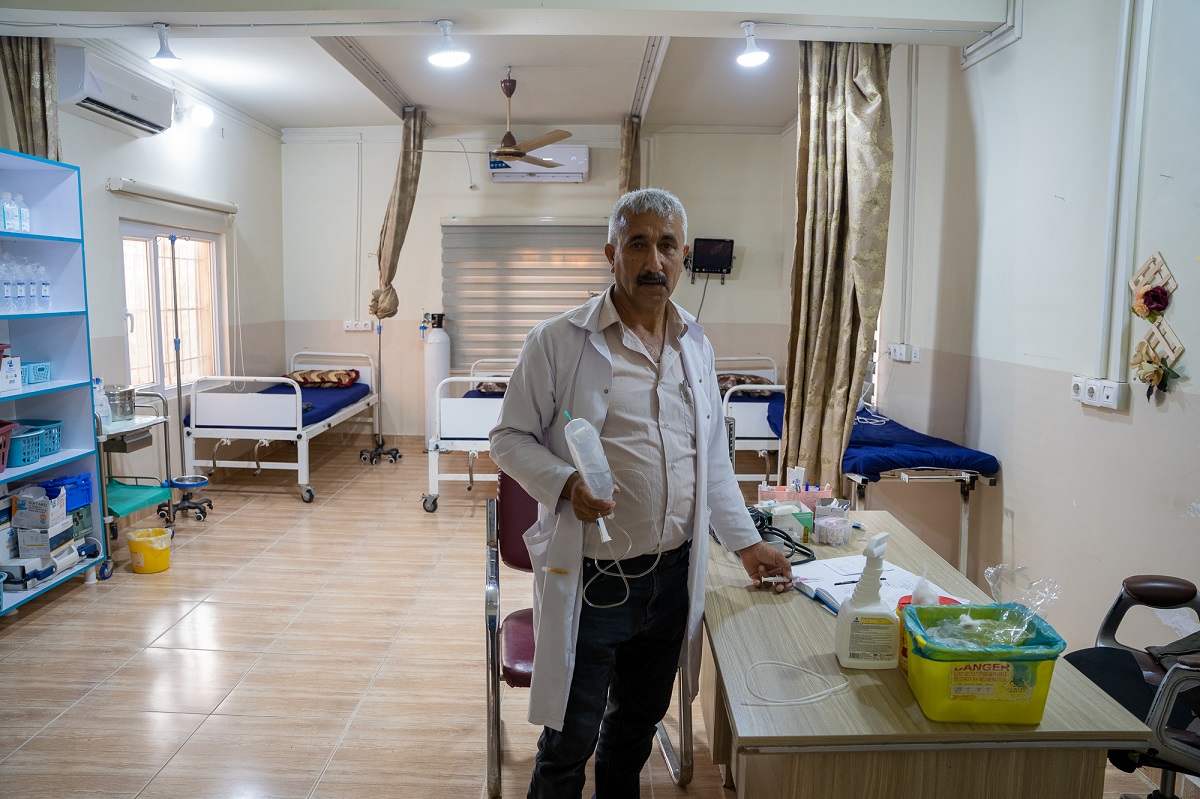 Medical staff standing in a room, behind him are hospital beds