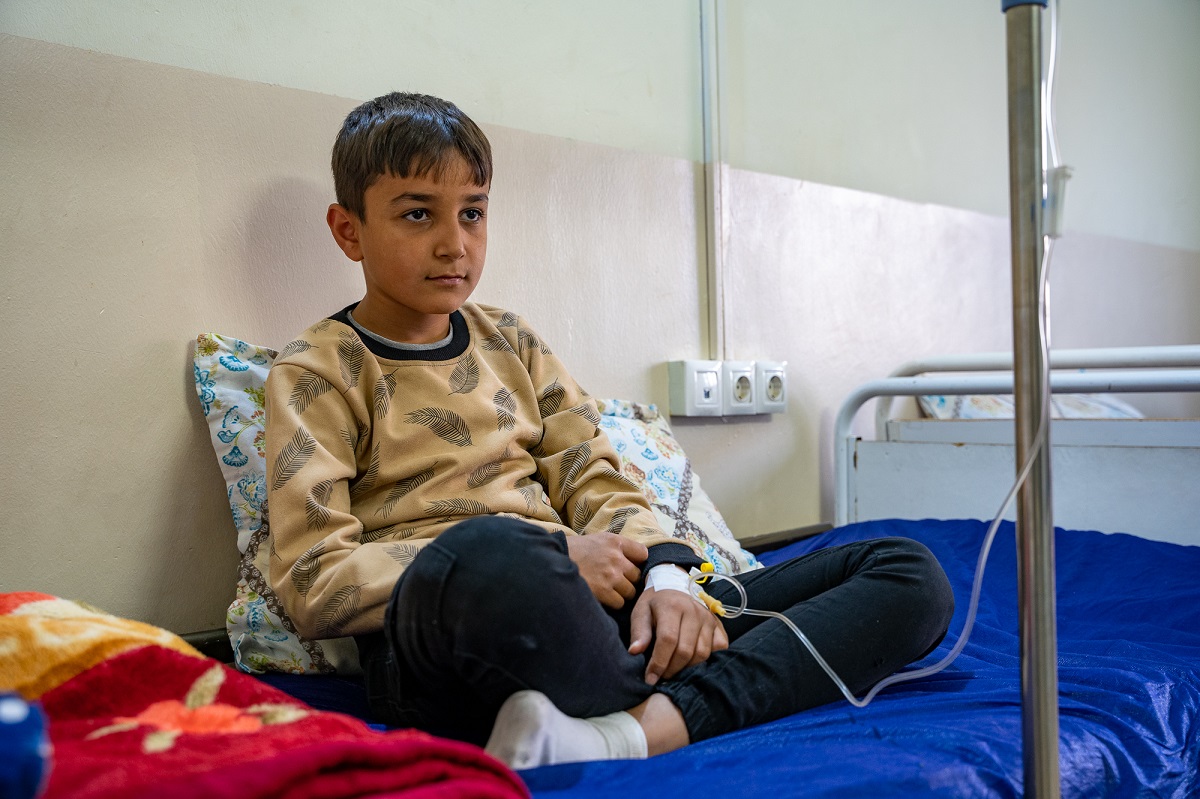 A boy sitting on a hospital bed, receiving treatment