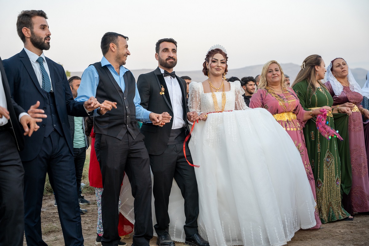 bride and groom dancing, holding hands with other people in a circle