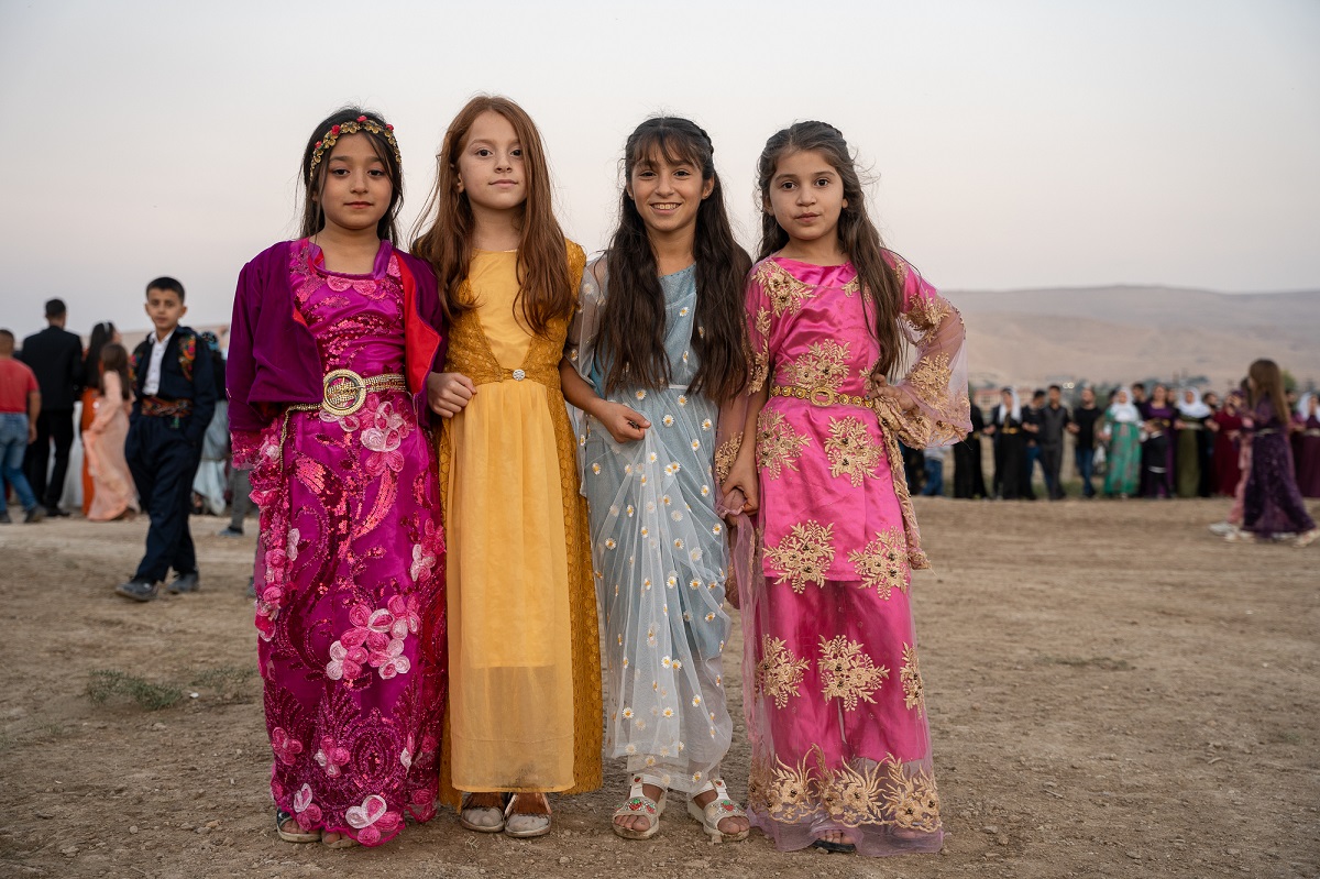 Young women dressed in traditional Kurdish clothing pose for a photo at the wedding celebration.
