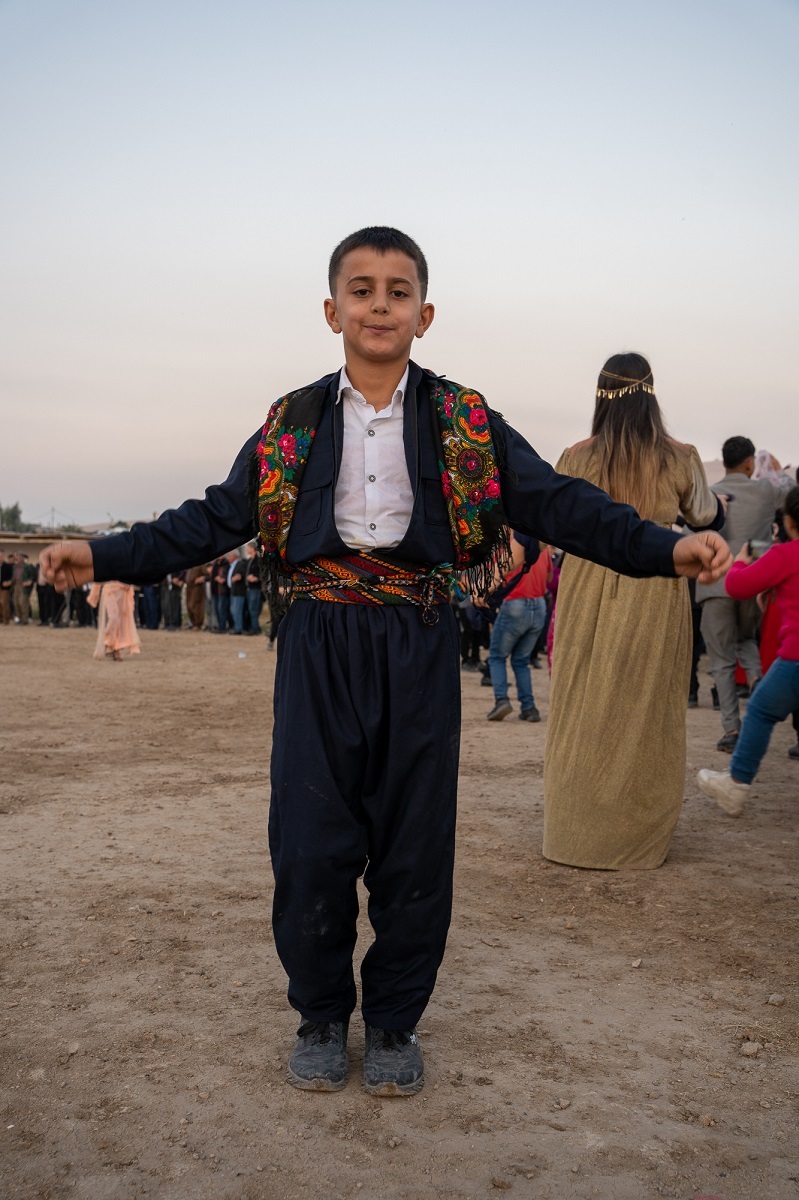 A young man dances at the wedding, dressed in traditional Kurdish clothing.   