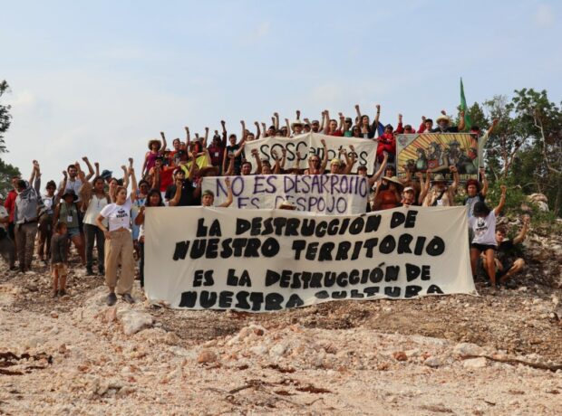 A group of activists stands with a poster on one of the construction sites of the Maya Train project