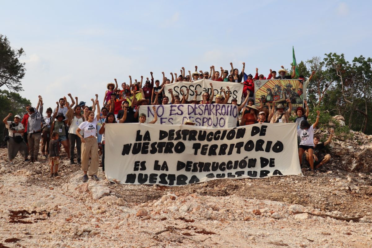 A group of activists stands with a poster on one of the construction sites of the Maya Train project
