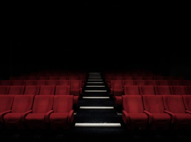 An empty cinema auditorium with red seats and dimmed lights