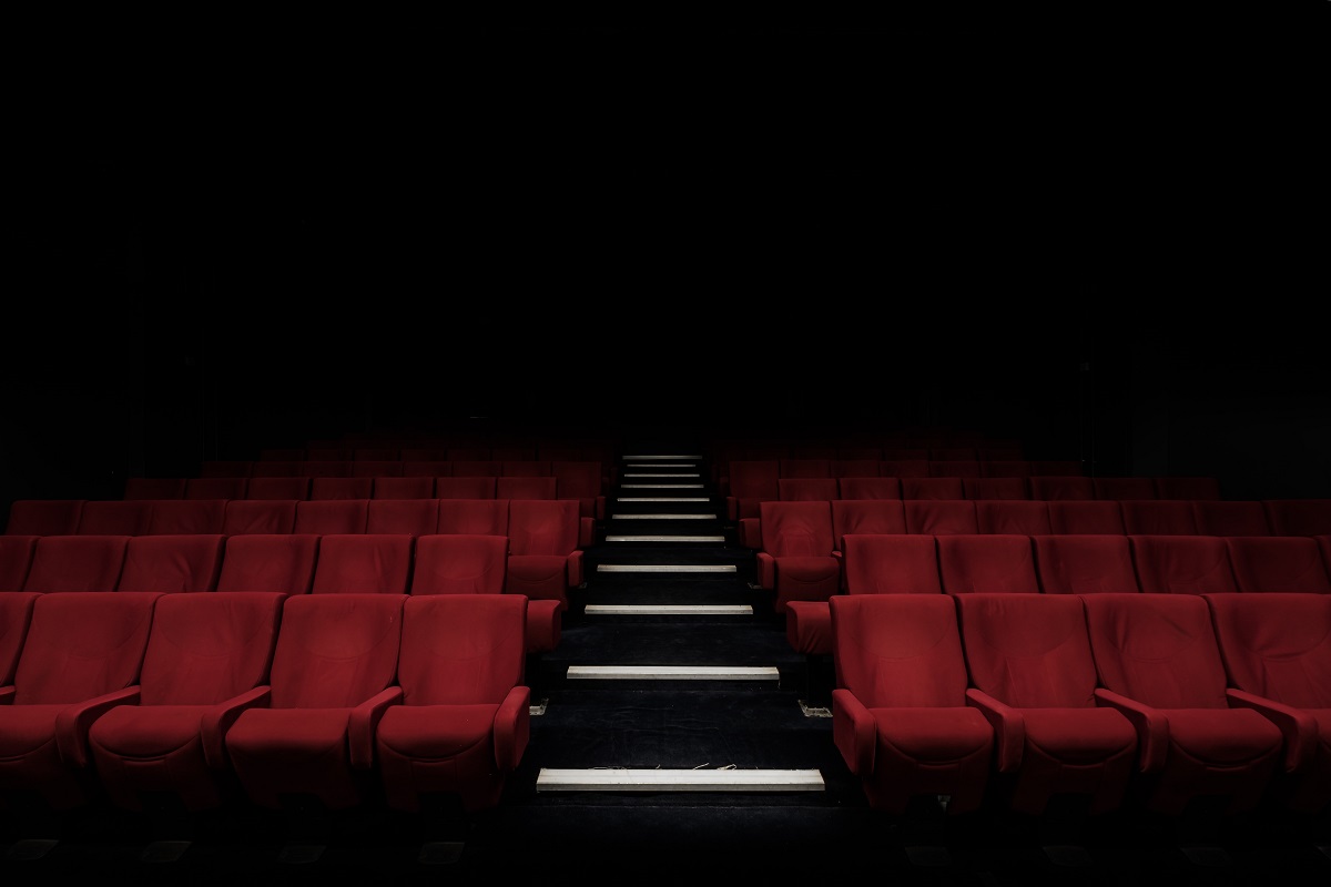 An empty cinema auditorium with red seats and dimmed lights