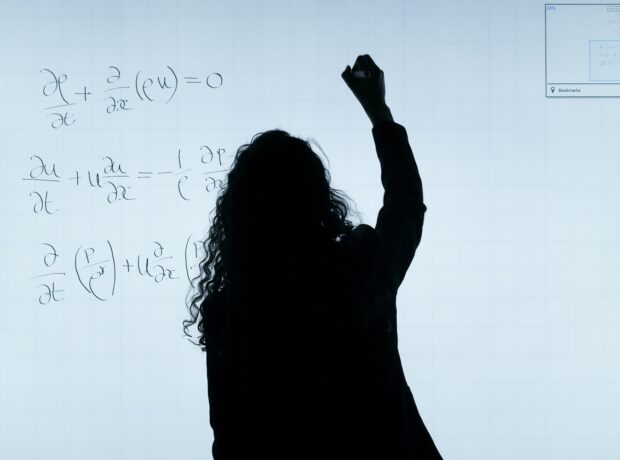The silhouette of a woman writing equations on a digital screen