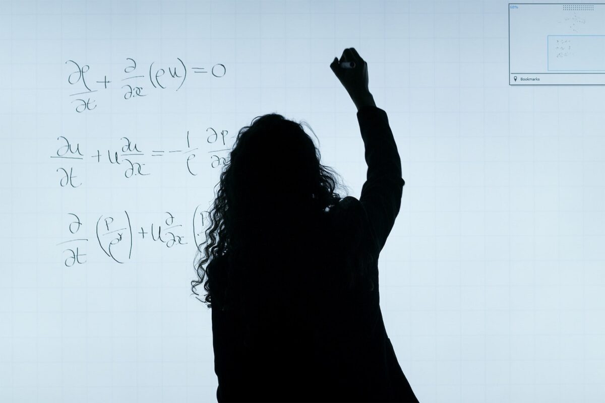 The silhouette of a woman writing equations on a digital screen