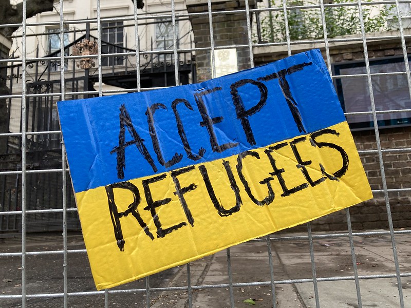 A cardboard sign painted the colours of the Ukraine flag reads "Accept refugees" 