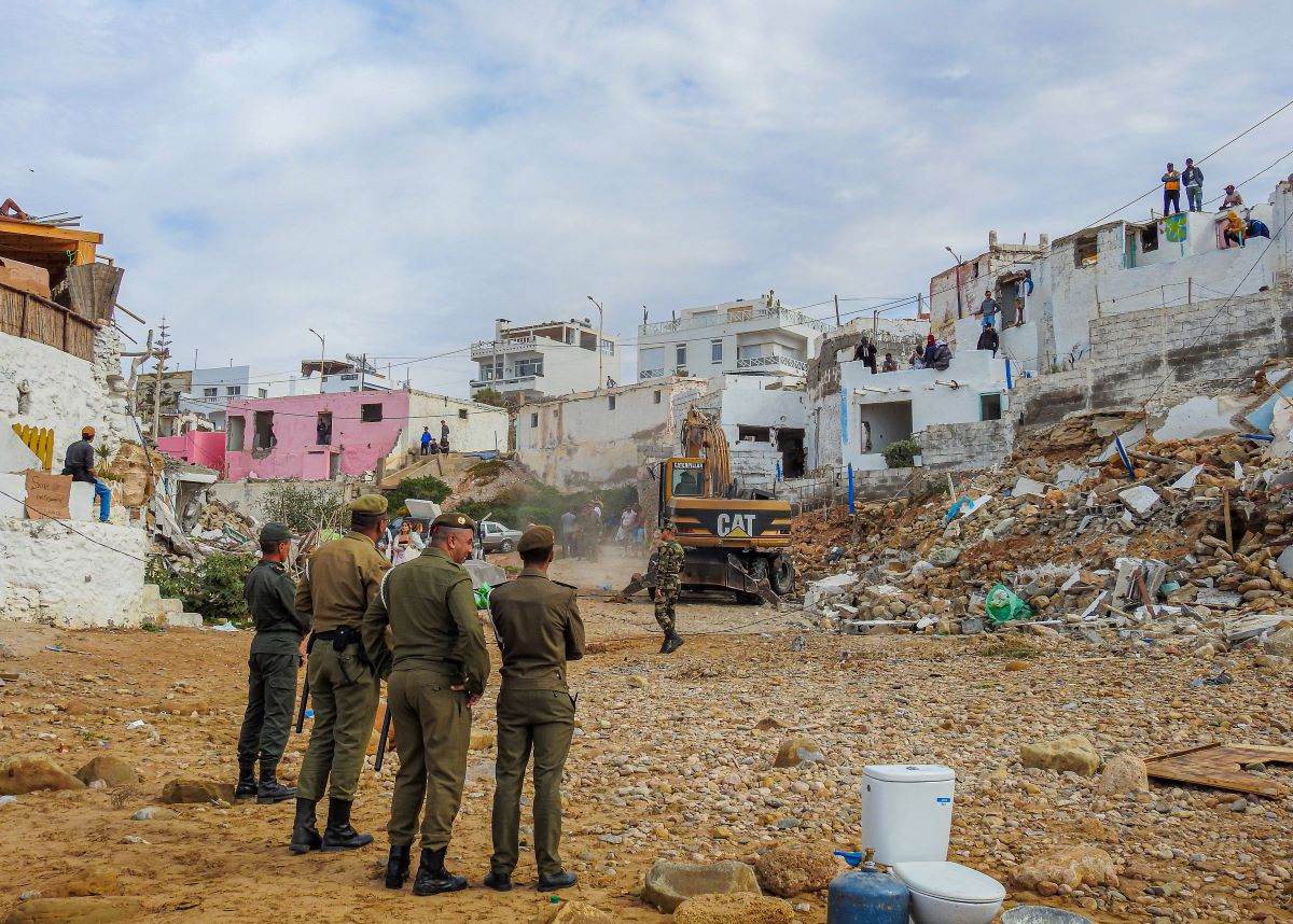 a demolition is taking place in a residential area with four uniformed army men watching