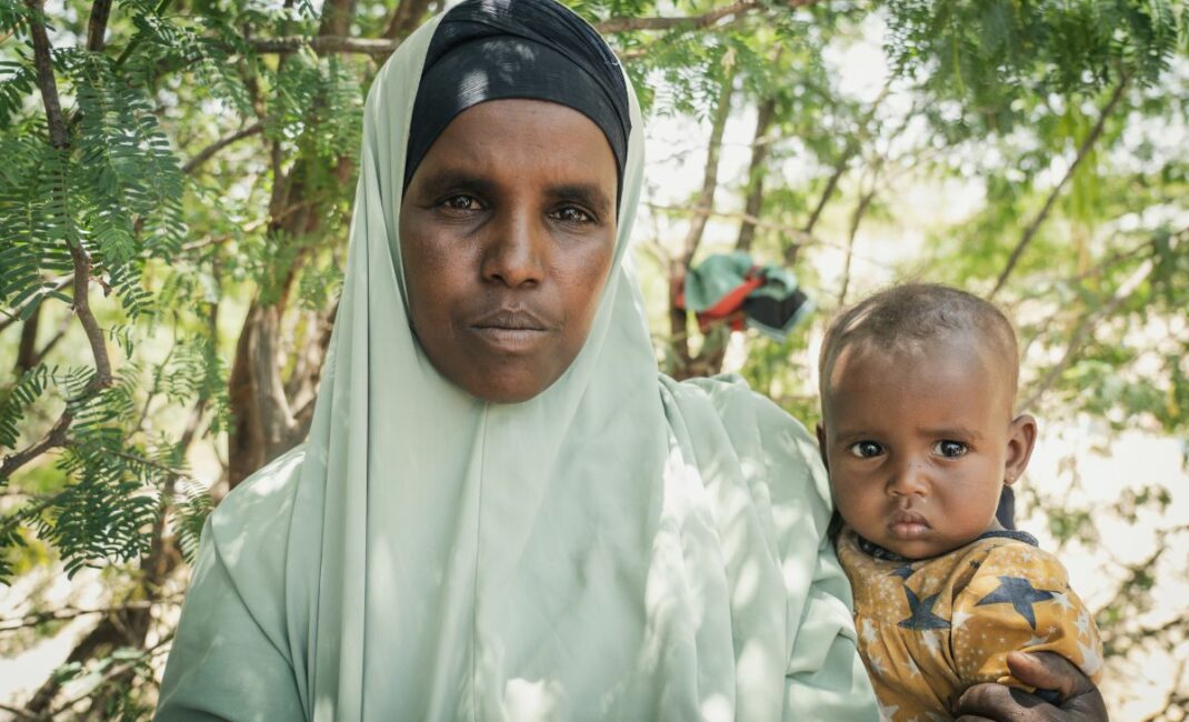 a veiled woman holds a baby and stares at the camera