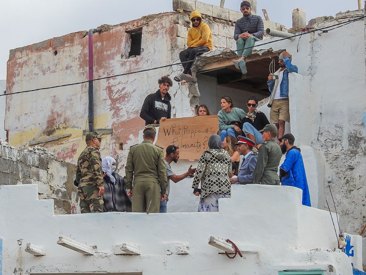 a group of people protesting a demolition speaks to the army