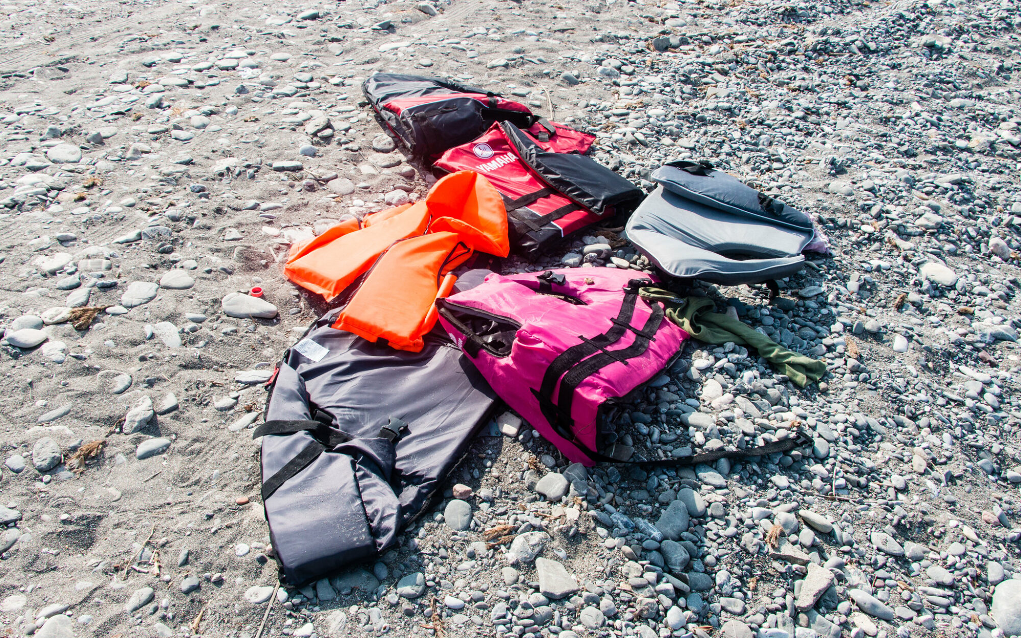 Six lifejackets lie scattered on a beach