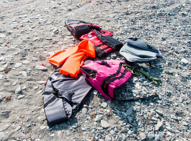 Six lifejackets lie scattered on a beach