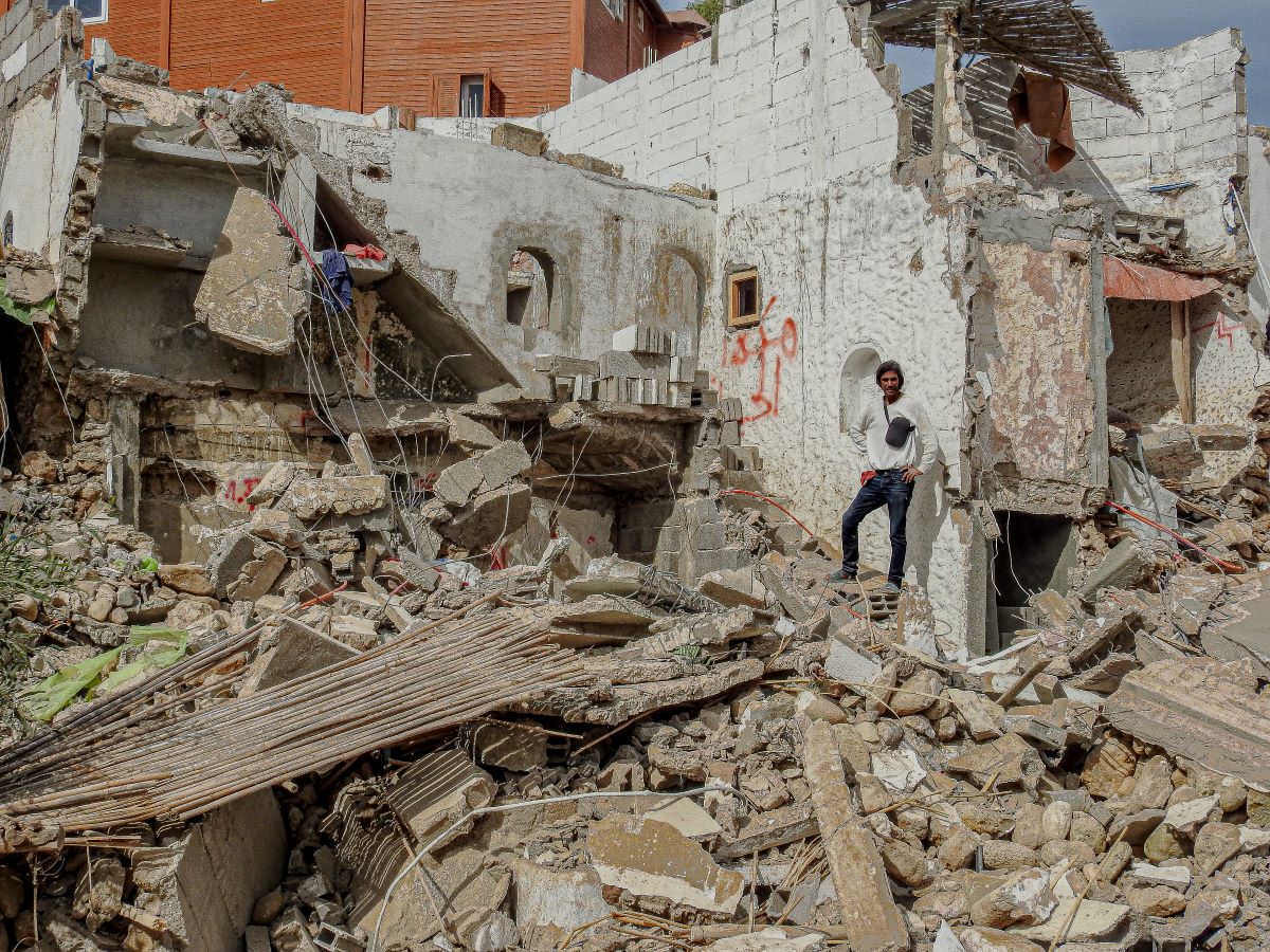 a man stands next to the rubble of a residential demolition