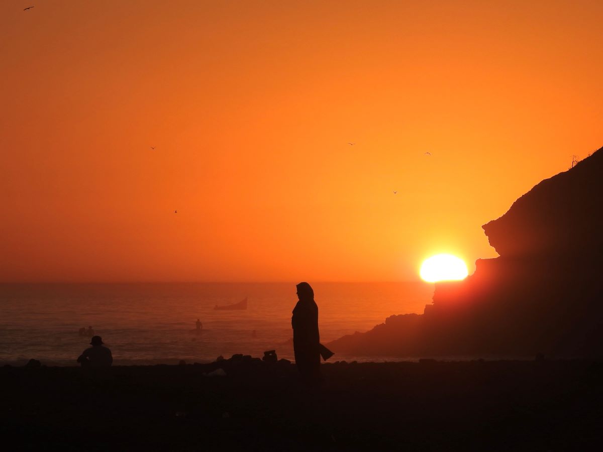 a woman's silhouette is made visible by a deep orange sunset behind her