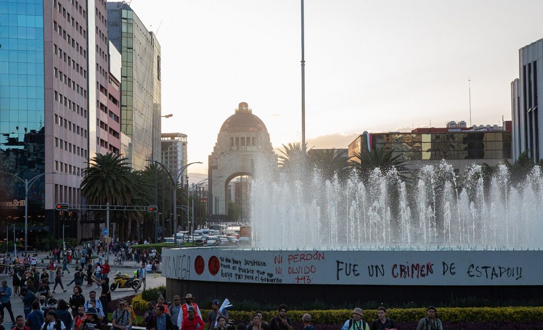 Graffiti on a large public fountain reads "Fue un crimen de estado!" (It was a crime of the state)