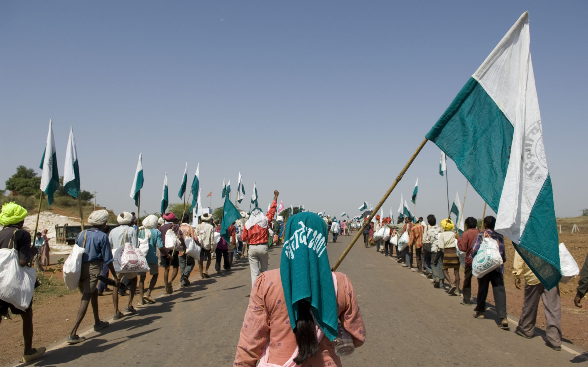 A woman, centre, holds a flag, flanked by two lines of protesters with flags on either side of the street