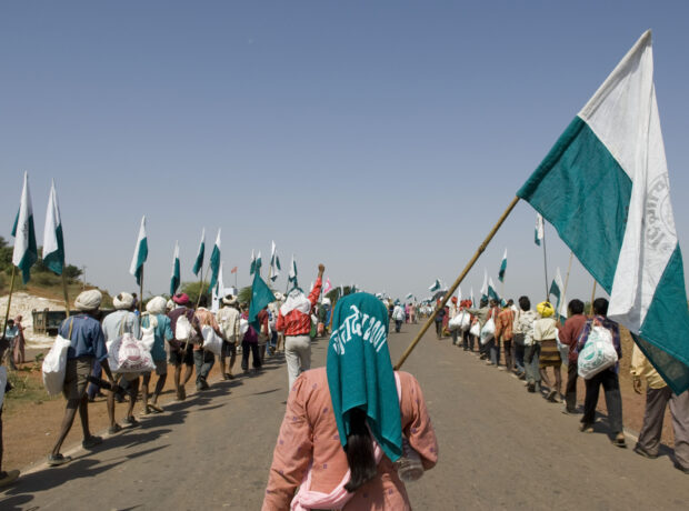 A woman, centre, holds a flag, flanked by two lines of protesters with flags on either side of the street