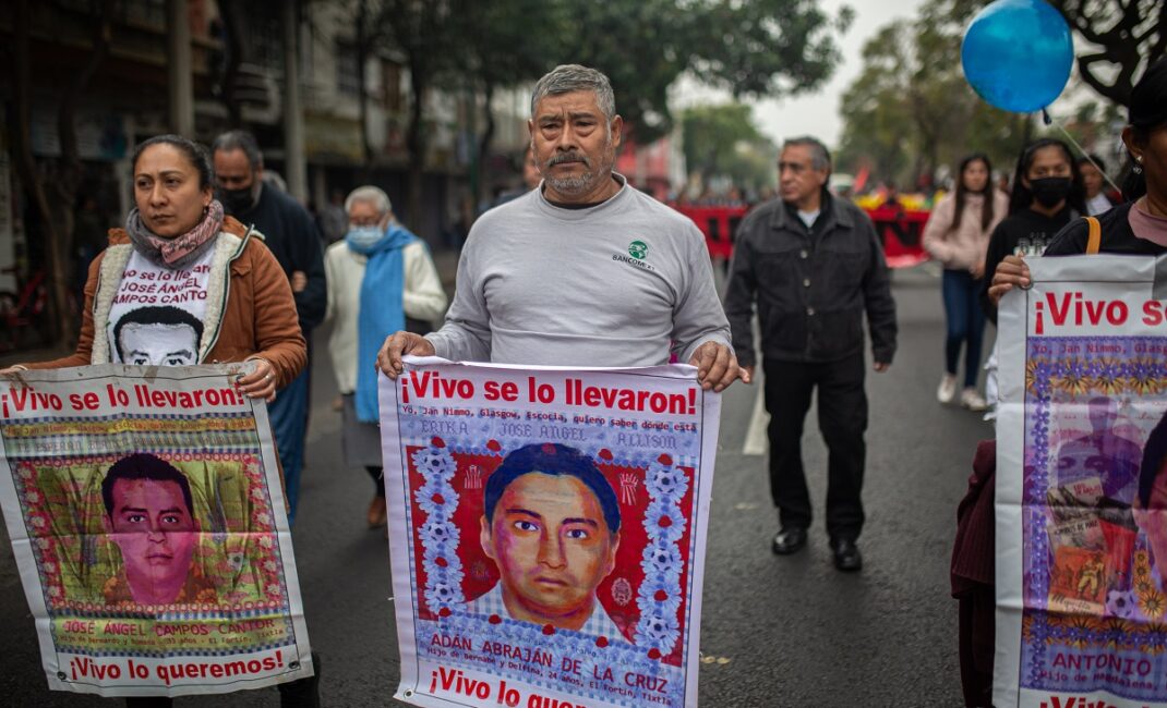 Parents hold images of their missing children at a protest against the forced disappearance of Los 43 de Ayotzinapa - by Paula González