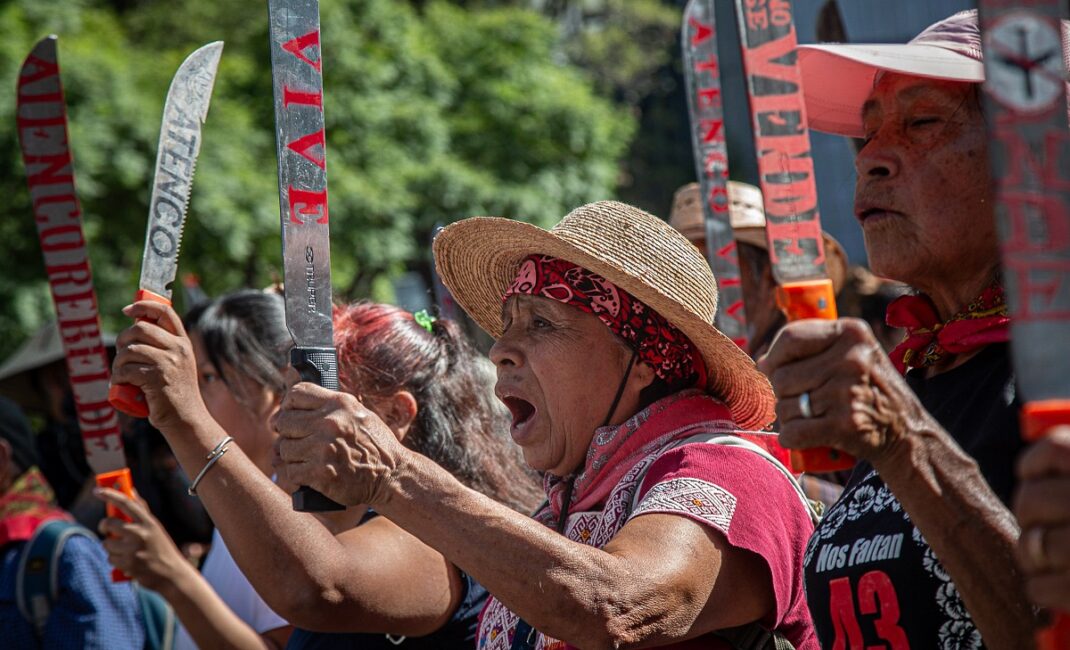 Women stand together raising machetes in their hands at the protest