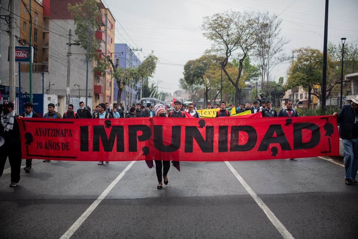 Students hold a long red banner reading "Ayotzinapa the years of impunity" - by Paula González