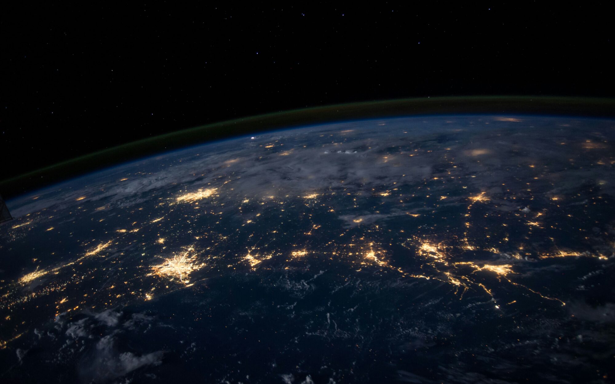 A satellite image shows the curve of the earth and cities lit up in darkness