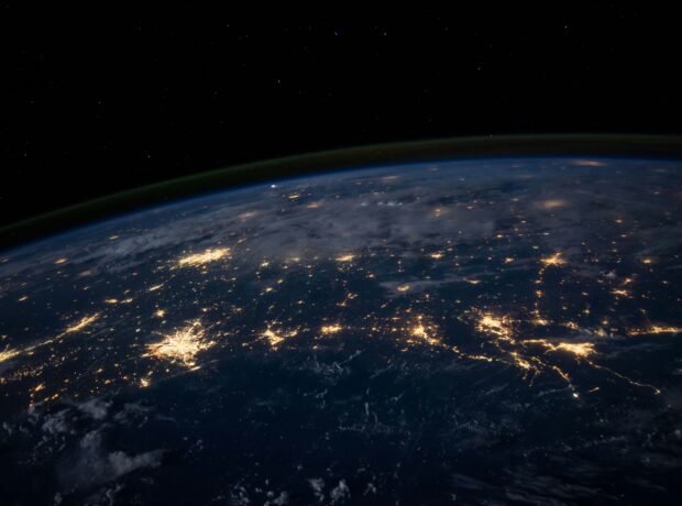 A satellite image shows the curve of the earth and cities lit up in darkness