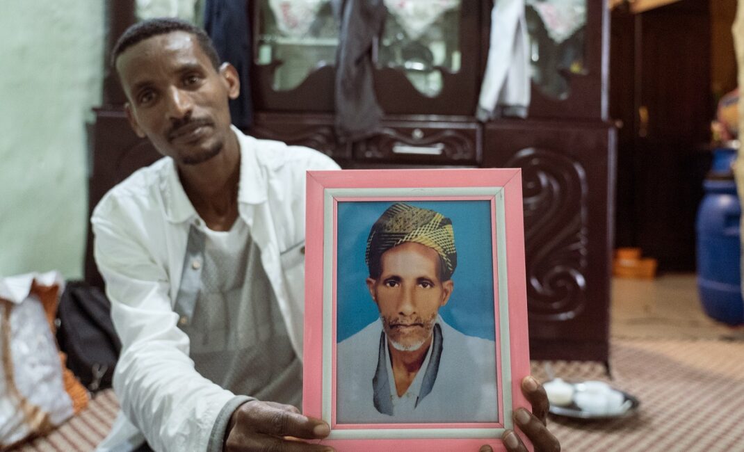 Photograph by Jaclynn Ashly showing an Ethiopian man, Abdul Kamal Legas, holding up a photo of his father Sheikh Kamal Legas.