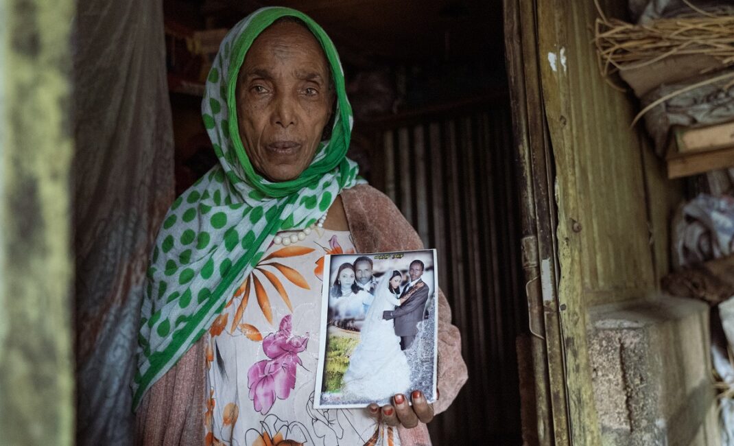 A woman wearing a green headscarf a string of white beads and a floral dress hold a picture of her son's wedding day:  Photograph by Jaclynn Ashly for Lacuna story on religious tensions in Ethiopia.