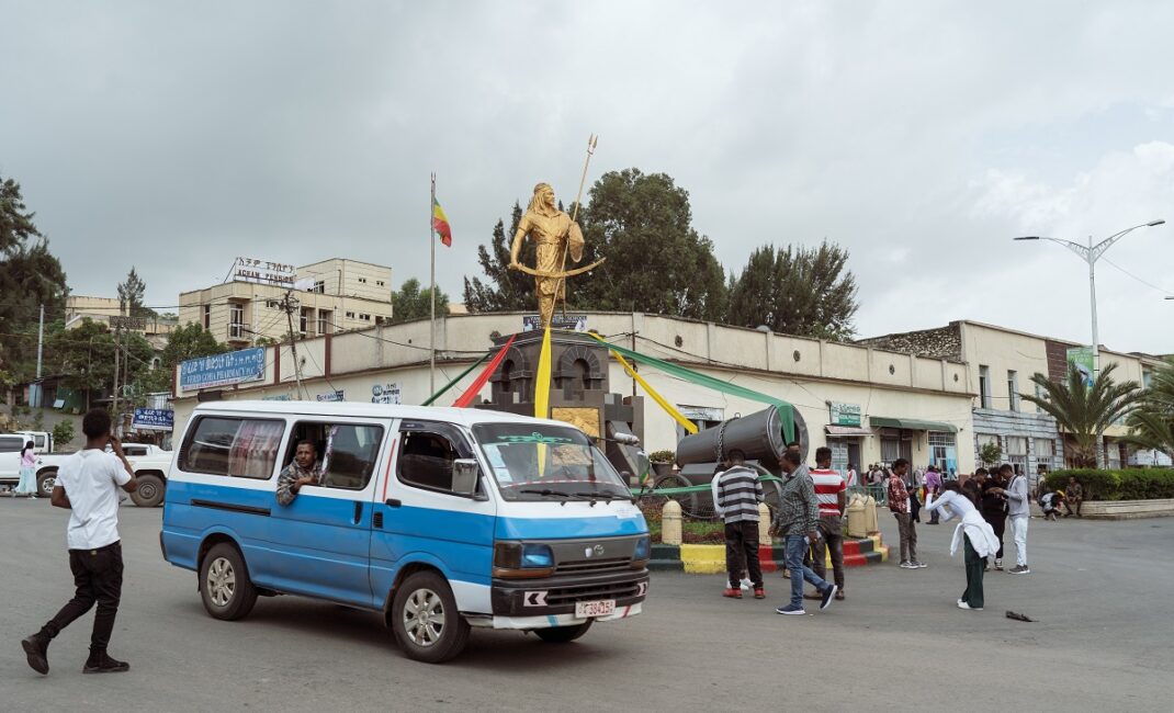  A statue of Emperor Tewodros II by roundabout in central Piassa neighborhood in Gondar. People are walking around and a blue and white van drives past:  Photograph by Jaclynn Ashly for Lacuna story on religious tensions in Ethiopia