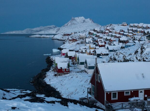 Photograph of Nuuk, Greenland's capital with wooden houses in the front and snowy mountains in the back; for Lacuna story on forced sterilisation in Greenland